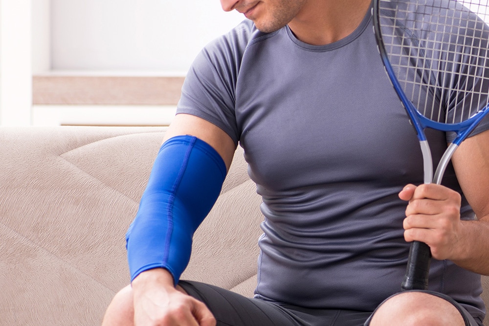 Cropped photo of male tennis player with strapped arm suffering from tennis elbow