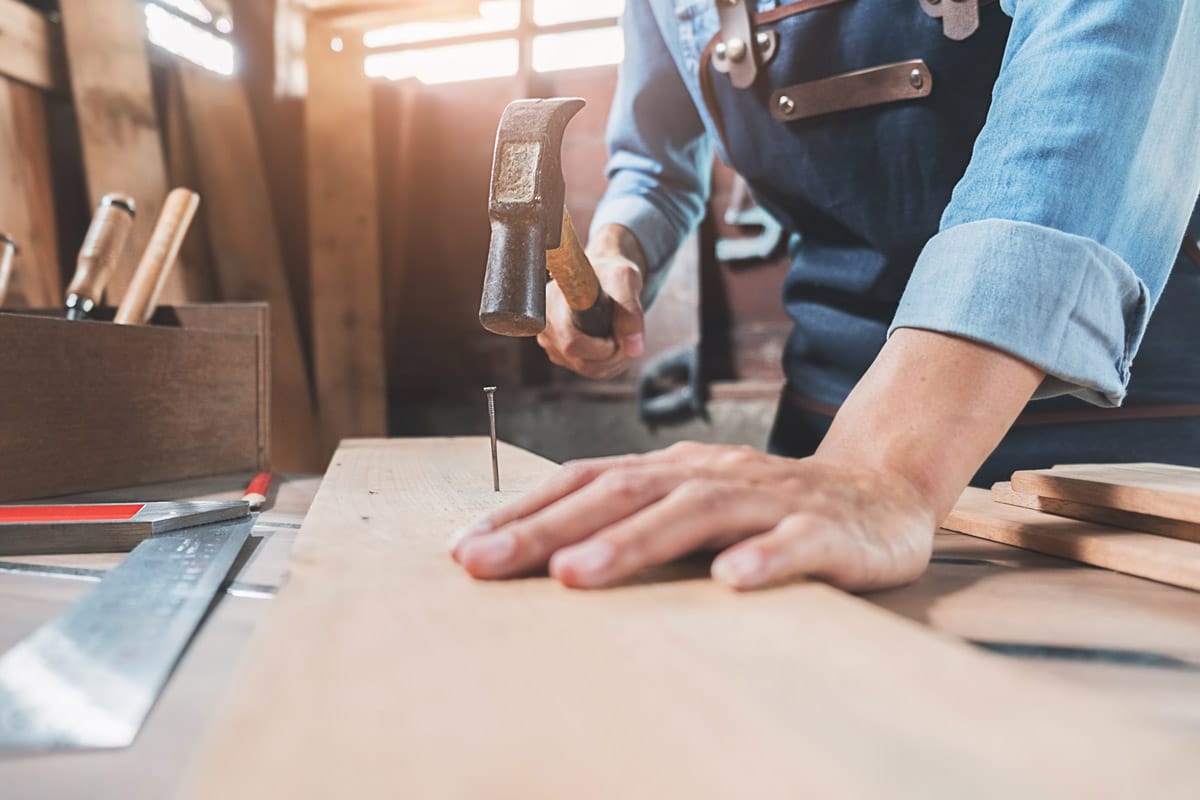 middle aged male working with timber in carpenters workshop following successful biceps tear treatment