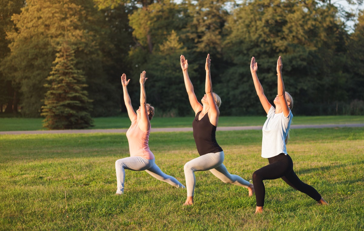 Three women performing moderate exercise in green parkland without pain from calcific tendonitis