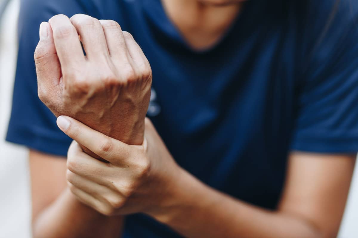 close up photo of man gripping his right wrist with his left hand from the pain associated with carpal tunnel syndrome