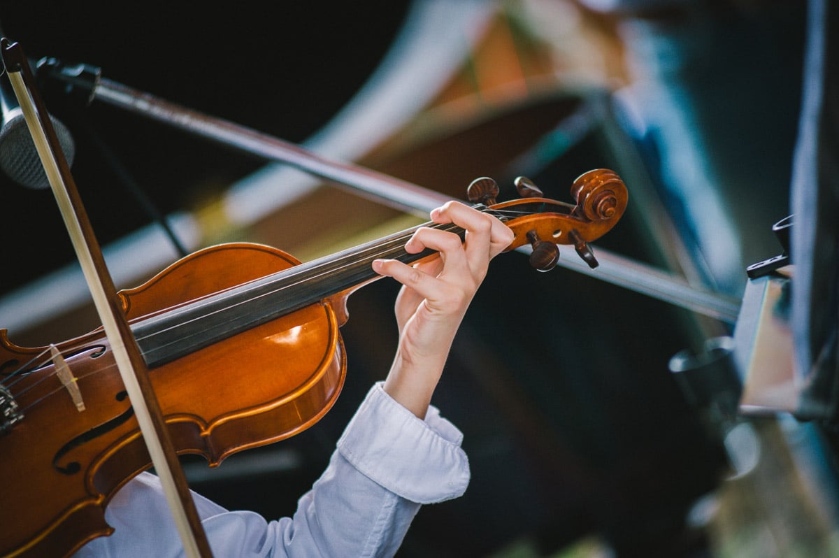 close up photo of woman in a blue long sleeve shirt playing a violin following her trigger finger release procedure